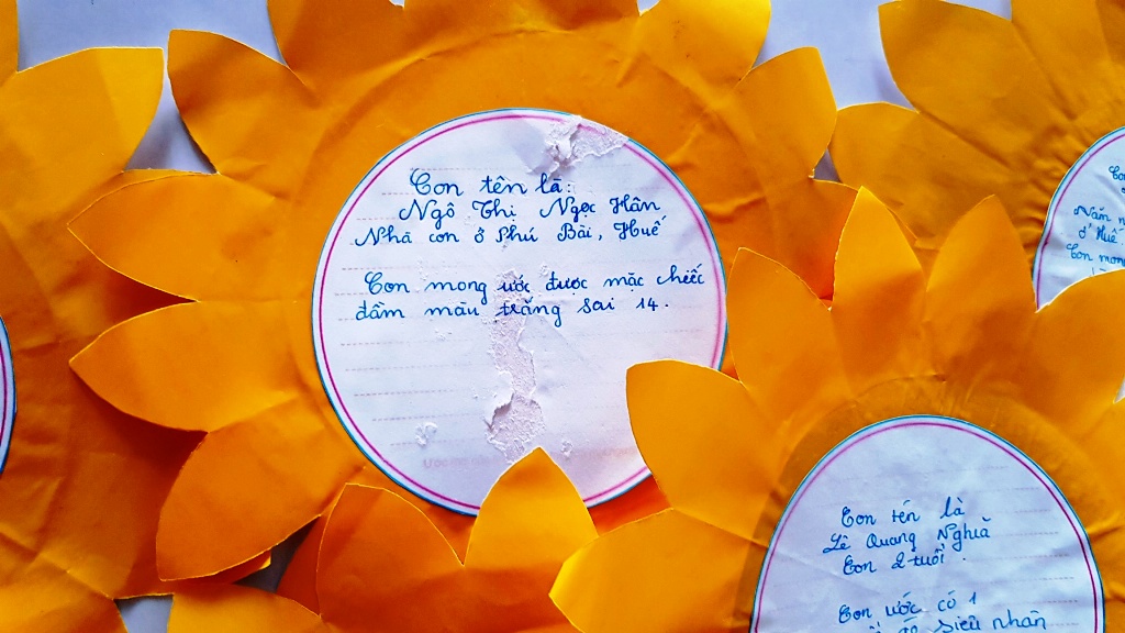 Ngọc Hân, a child patient, expresses her simple wish on a sunflower: owning a white dress
