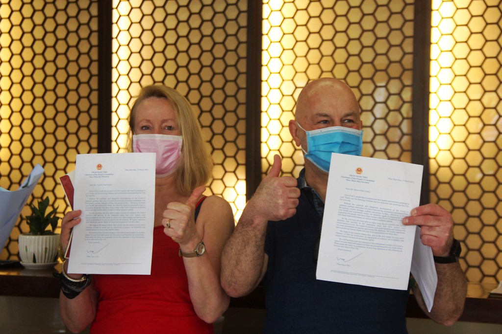 Two foreign tourists giving thumbs up sign to show their satisfaction when receiving a letter from Chairman of Provincial People's Committee Phan Ngoc Tho after the quarantine.
