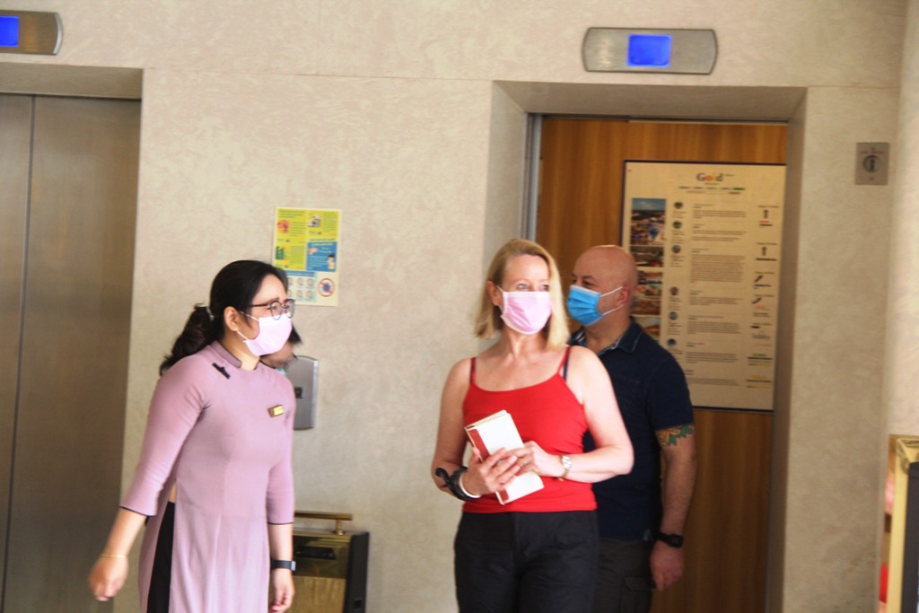 Two foreign tourists stepping out of the elevator at the Gold Hotel after their quarantine period, and being delighted to receive a warm welcome from the local authorities.