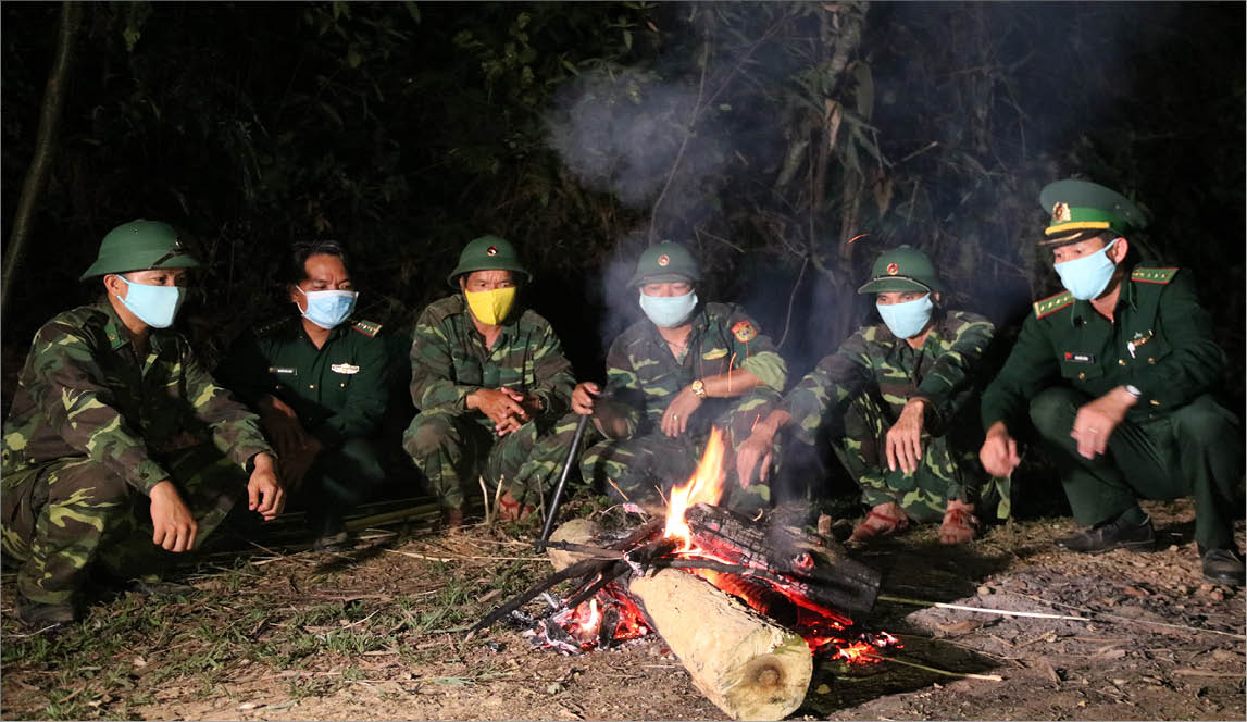 In the cold late-night, the soldiers warm up by the fire while on duty