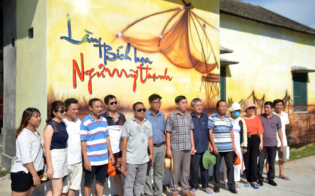 The delegation taking a souvenir photo on the side of Ngu My Thanh fresco street