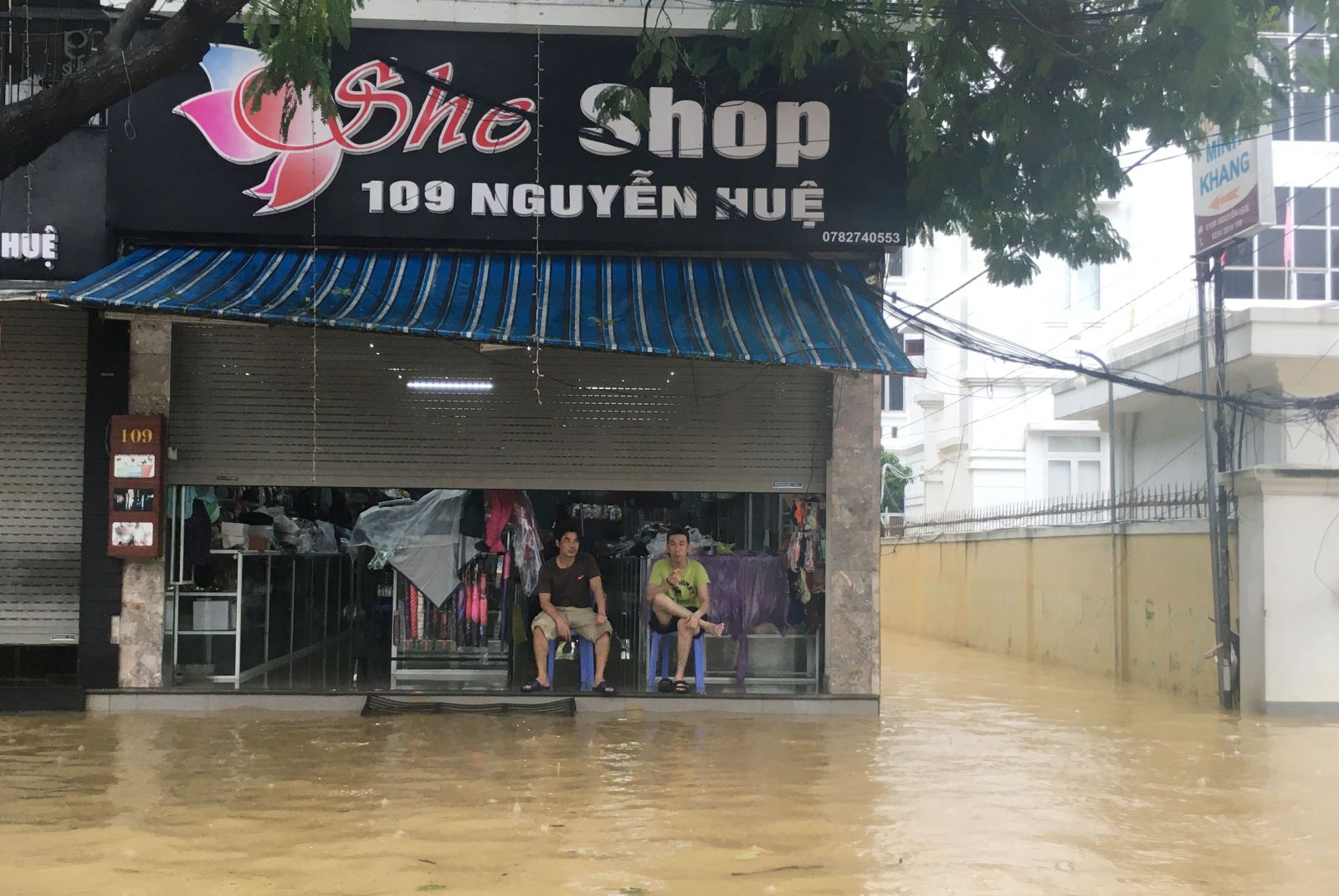 Các cửa hàng, cửa hiệu hoặc đóng cửa, hoặc ngồi ngắm cảnh nước lụt.