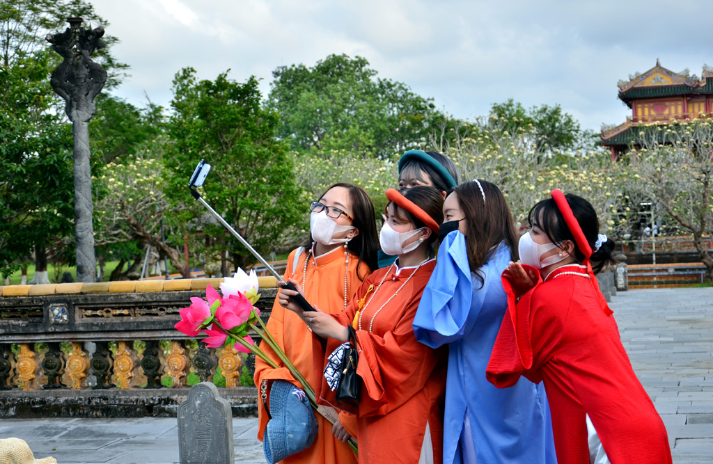 A group of young tourists from Hanoi wearing five-panel ao dai and having their photos shot in the Imperial City