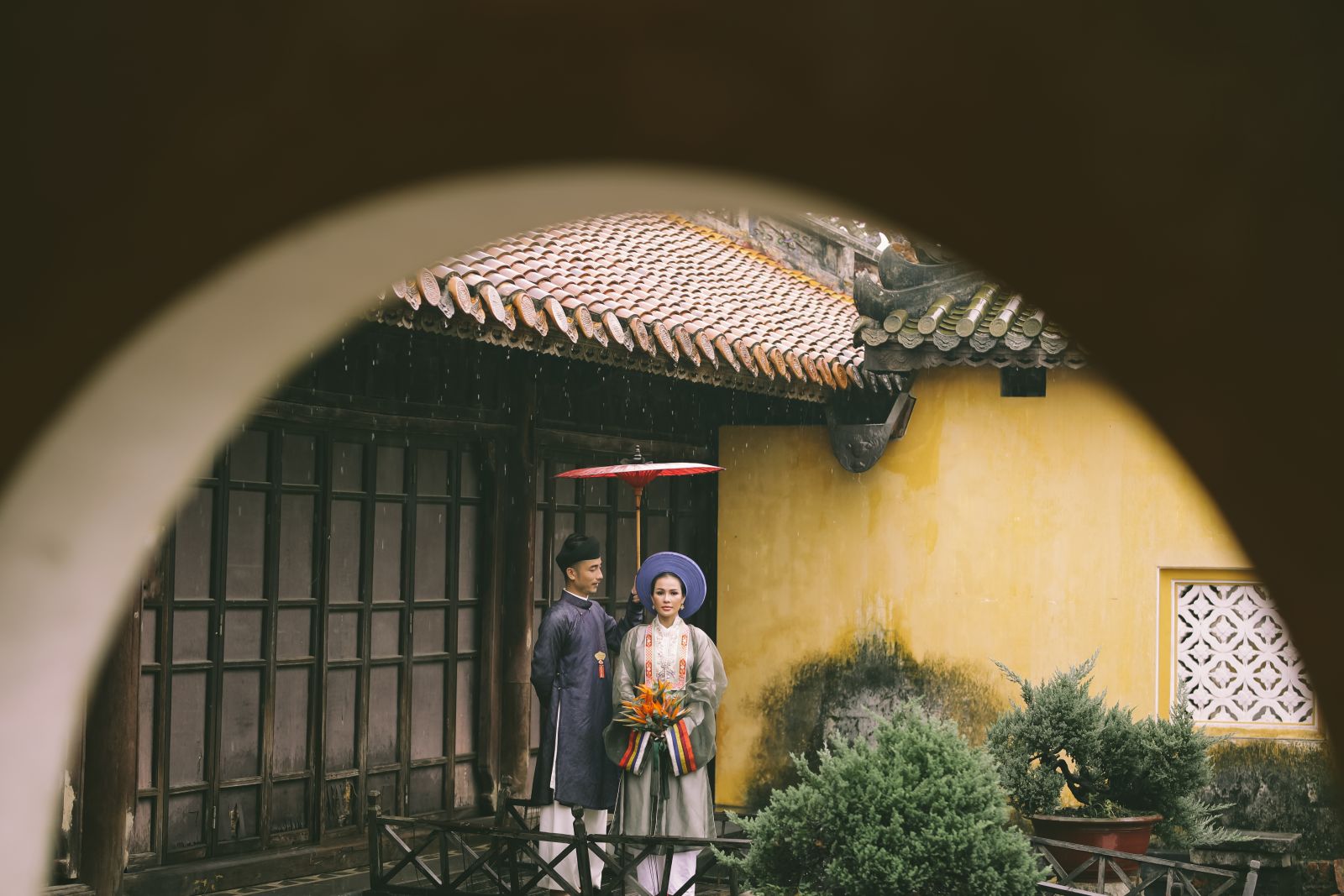 A young couple in traditional clothes taking wedding photos in the rain in the Imperial Citadel