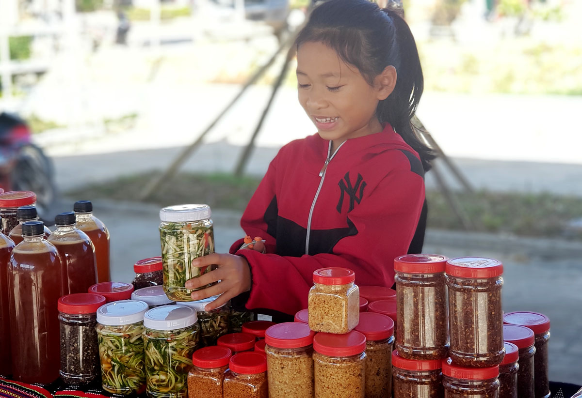 A little girl displaying salted and pickled scallion heads cooked by her family